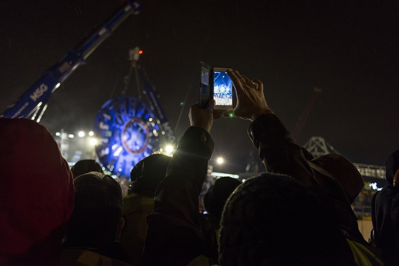 Le public de dos et de nuit, observe le lever de la roue de coupe du tunnelier, sur le chantier de Champigny lors du KM3