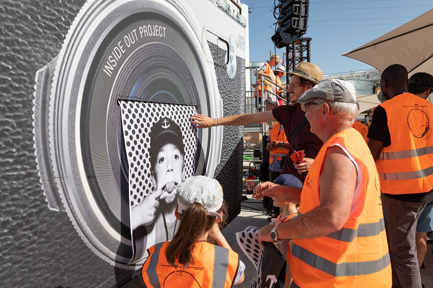 Camion-laboratoire photographique de l’artiste JR, des passants se font tirer le portrait en grand format en noir et blanc à Vitry dans le cadre du KM6