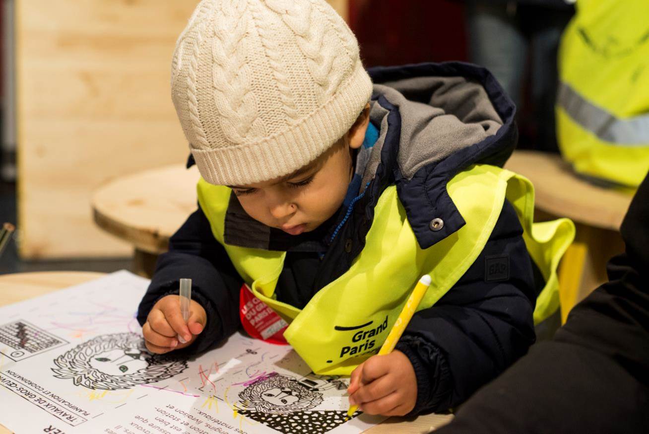 Enfant en gilet jaune de chantier dans un atelier jeunesse animé par « Les classes du Grand Paris Express », programme jeunesse de la Société du Grand Paris