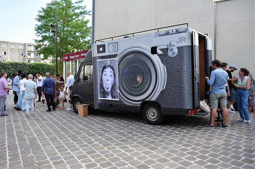 Camion-laboratoire photographique de l’artiste JR, des passants se font tirer le portrait en grand format en noir et blanc à Vitry dans le cadre du KM6