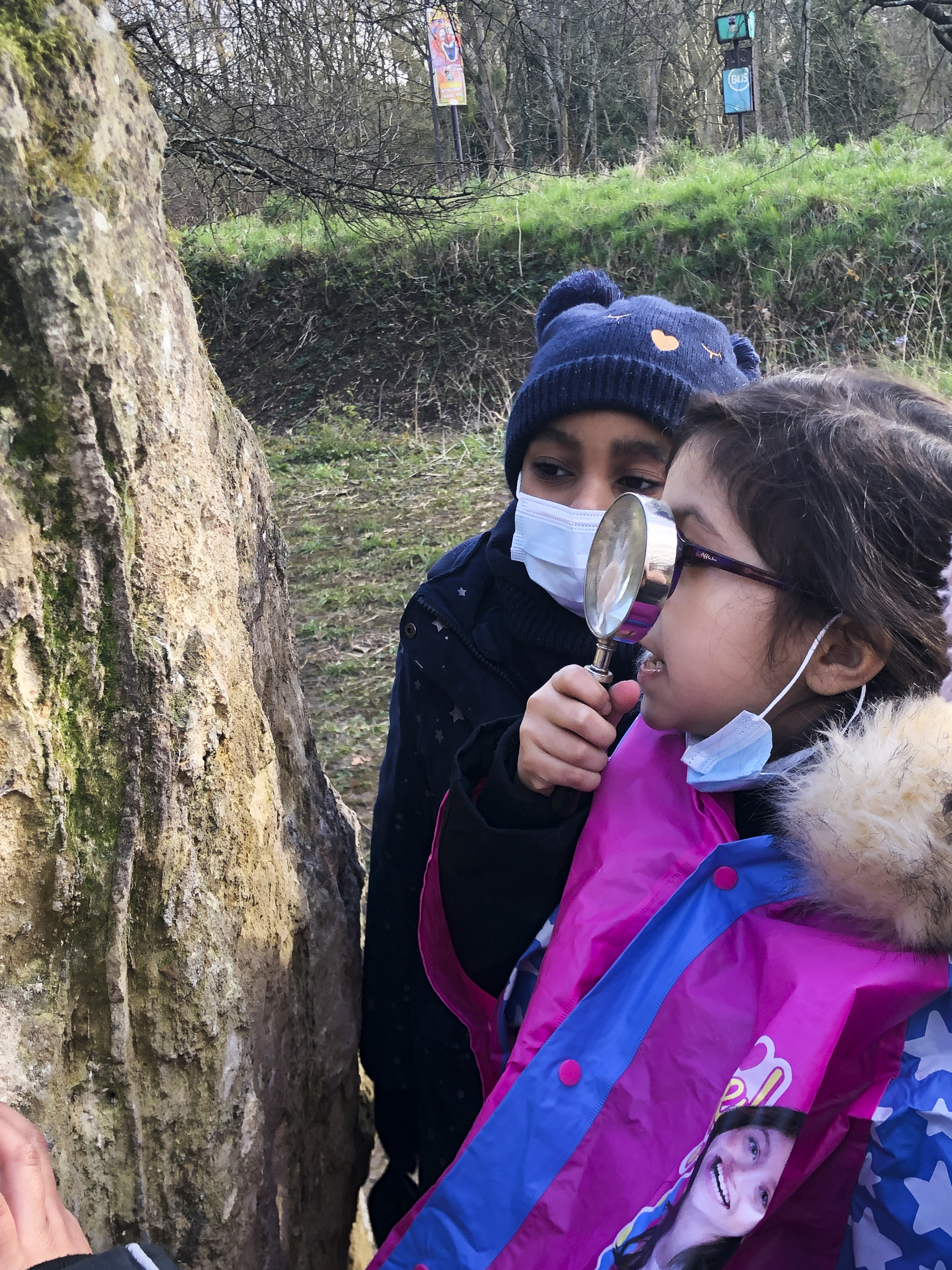 enfant regarde à la loupe la pierre