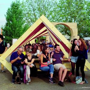 Festivaliers installés sur un mobilier urbain en bois