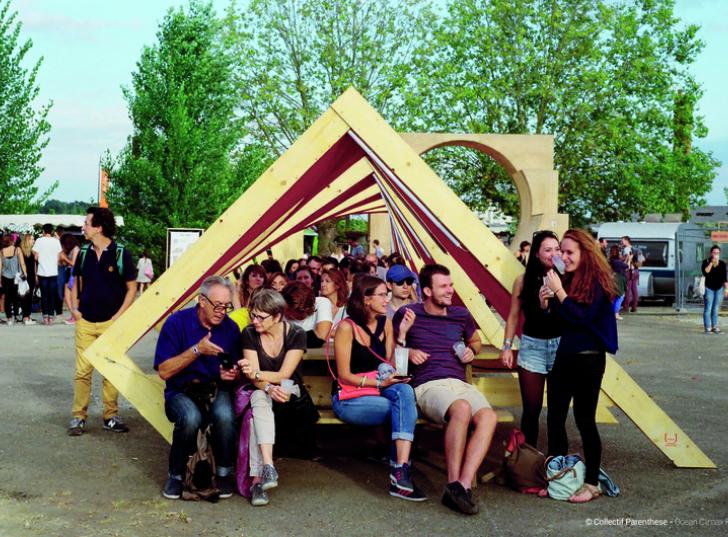 Festivaliers installés sur un mobilier urbain en bois