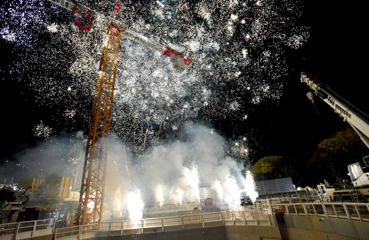 Le public en gilet orange de chantier profite du feu d’artifice tiré par Pierre de Mecquenem sur le chantier dans le cadre du KM9 à Massy 