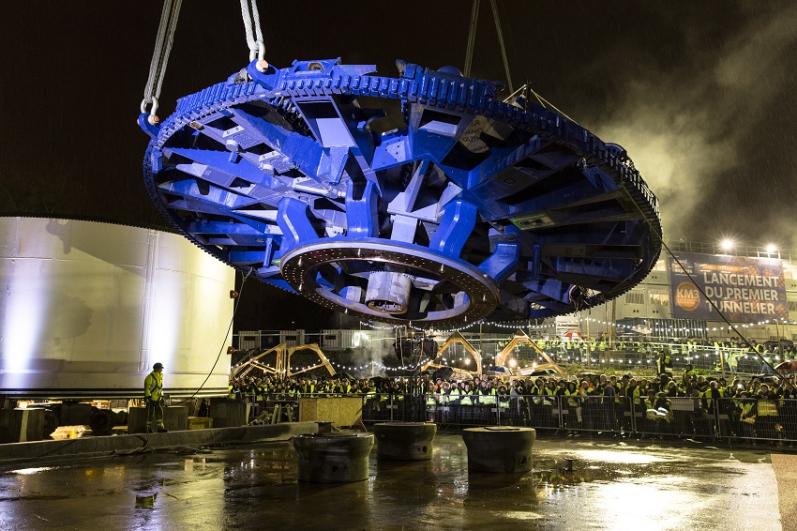 Le public en gilet jaune de chantier, de nuit, observe le lever de la roue de coupe du tunnelier, sur le chantier de Champigny lors du KM3