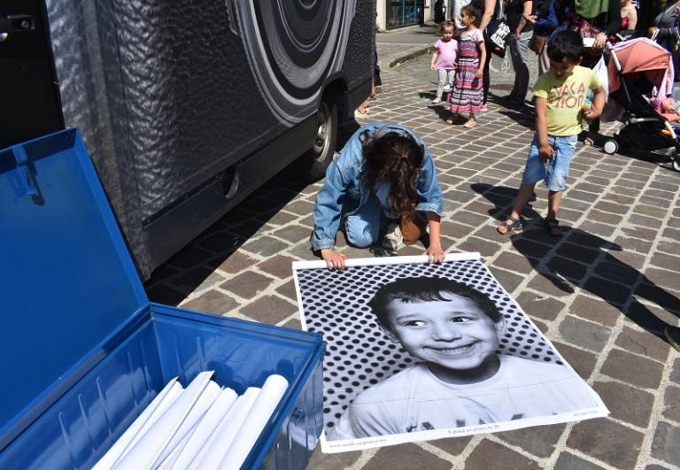 Camion-laboratoire photographique de l’artiste JR, des passants se font tirer le portrait en grand format en noir et blanc à Vitry dans le cadre du KM6