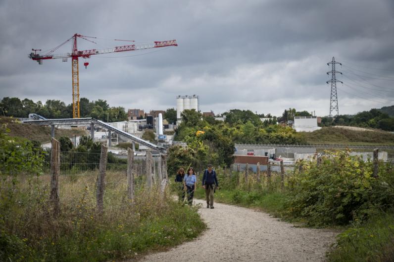 Trois marcheurs devant un ouvrage du Grand Paris Express au Mont Guichet, à Chelles