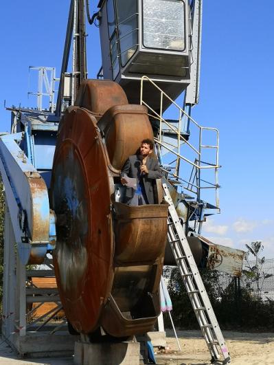 Un engin de chantier avec une roue de grande taille et un danseur avec un grand tissu, dans le cadre du projet de la Compagnie Tangible à Vitry-sur-Seine